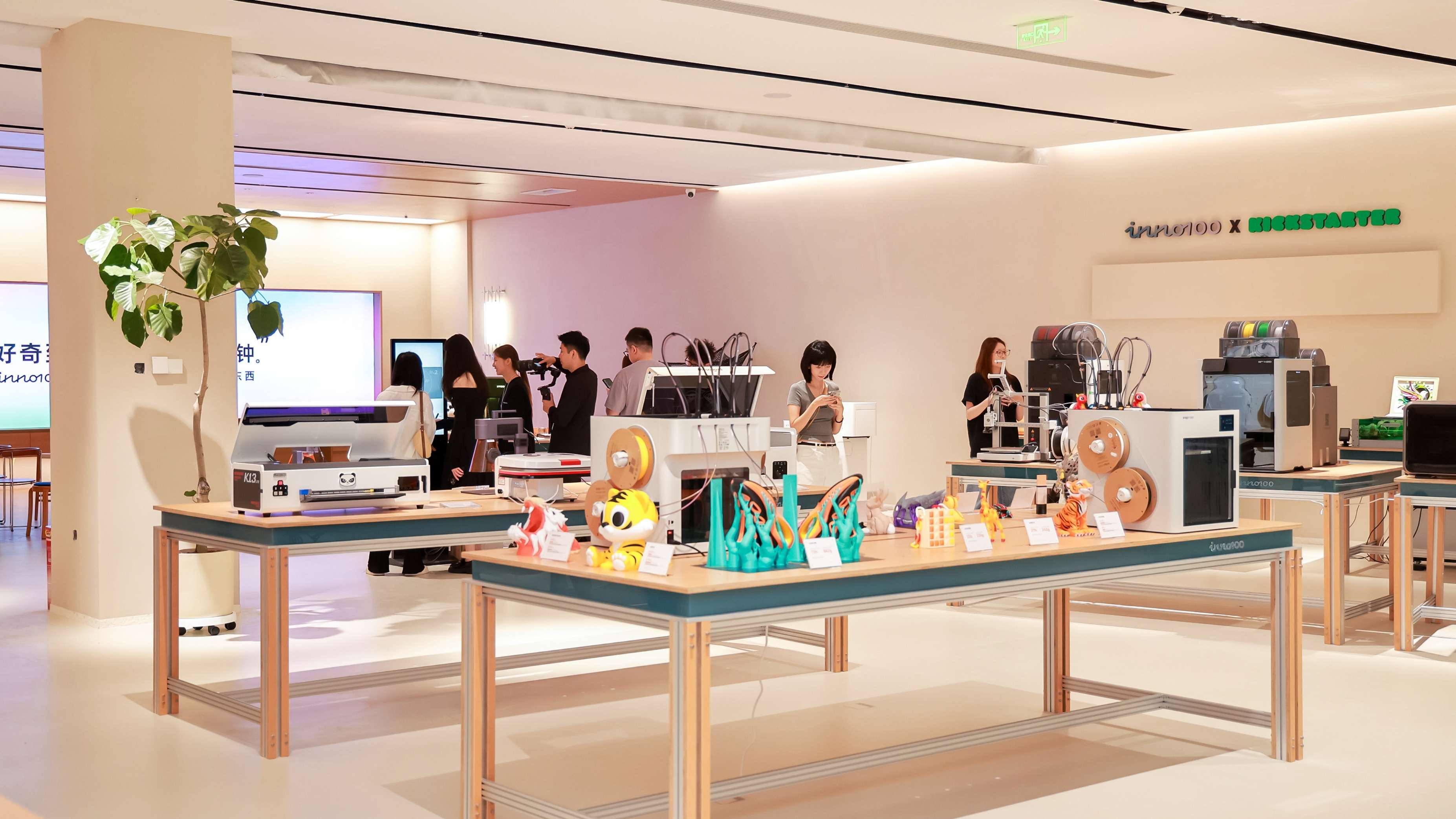 Visitors and staff explore consumer technology products displayed on tables within the INNO100 flagship store, featuring Kickstarter-backed hardware