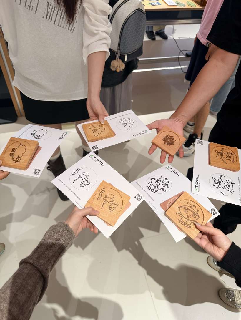Visitors at the INNO100 flagship store holding up wooden coasters engraved with various designs during a hands-on tech experience