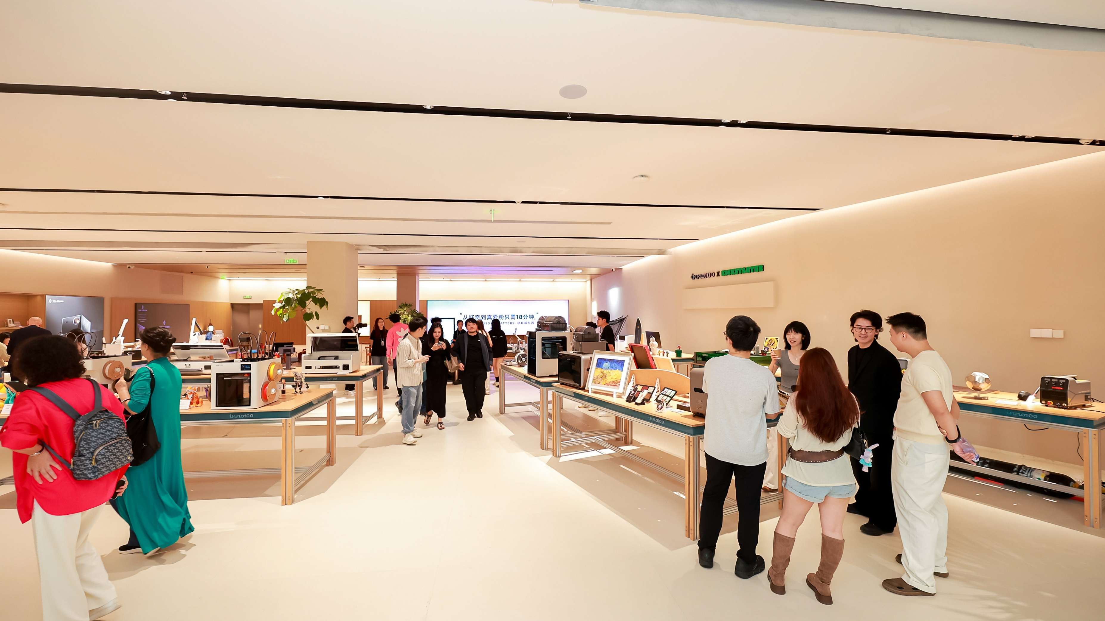 Visitors explore the INNO100 flagship store, browsing various consumer technology products displayed on wooden tables throughout the modern retail space