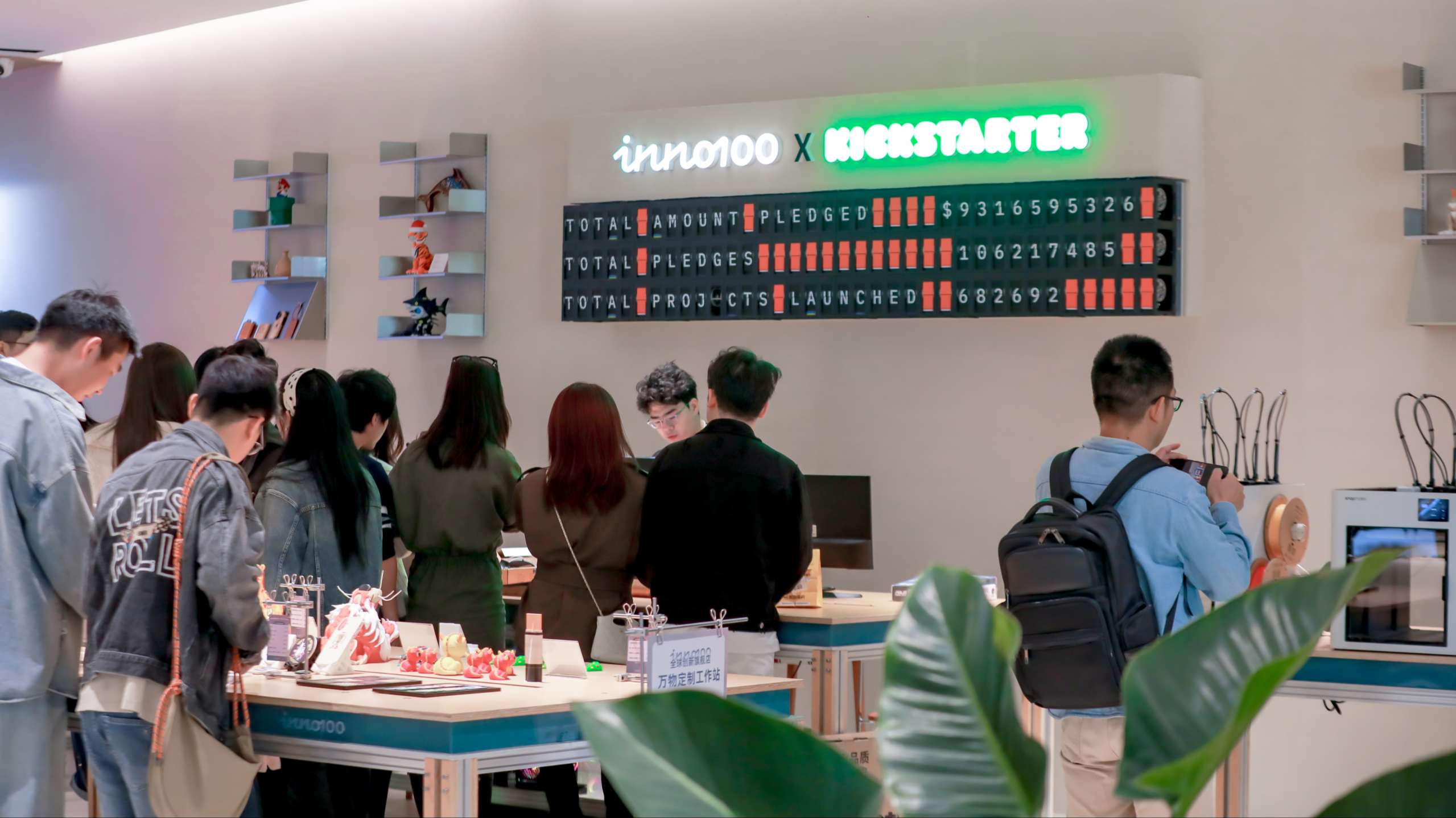 Visitors explore the INNO100 retail space featuring a digital display of Kickstarter project statistics and various consumer technology products on display